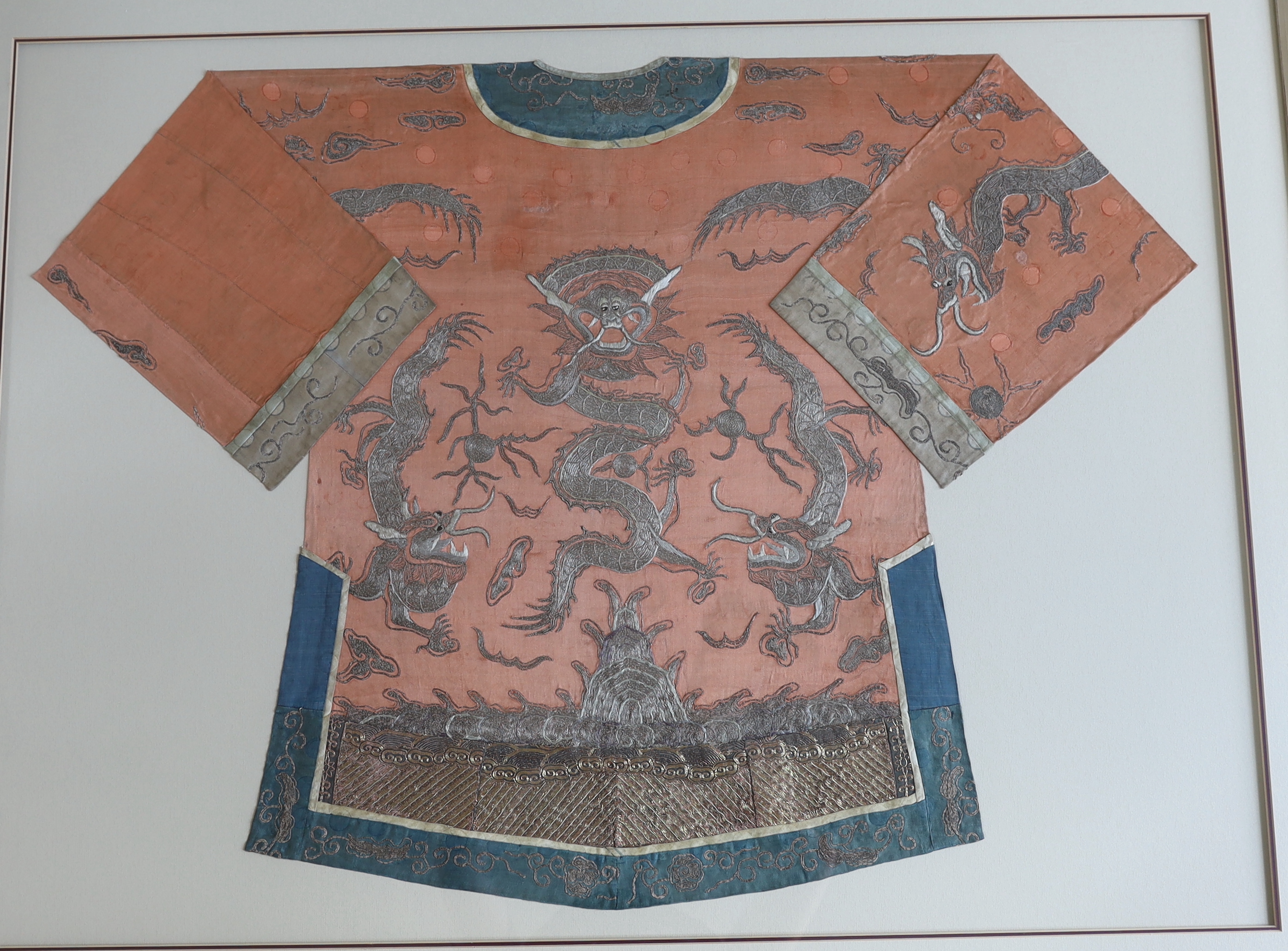 A late 19th century Chinese coral silk and silver metallic embroidered dragon robe, the dragons surrounded by auspicious embroidered symbols. The robe, split into back and front panels, separately framed within a deep do